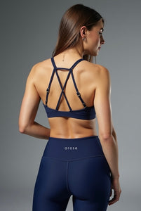 Woman wearing a navy sports bra and leggings with 'arose' branding on a gray background. Milf workout set
